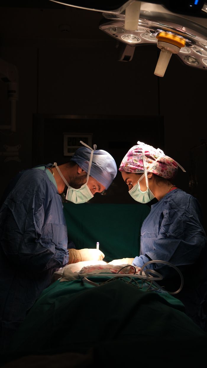 Focused surgeons performing surgery under dramatic lighting in a hospital operating room.